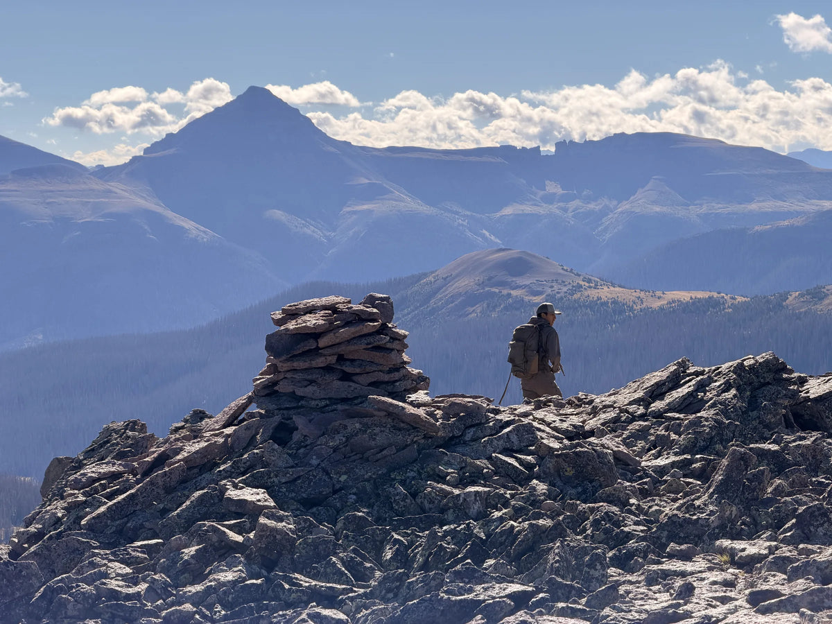 Stone cairn on a rocky summit with a distant peak beyond